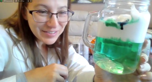 Compass Online teacher Ms. Angelo teaches a fun virtual Spooky Science class - it looks like she has created a white precipitate in a green liquid inside a mason jar mug.