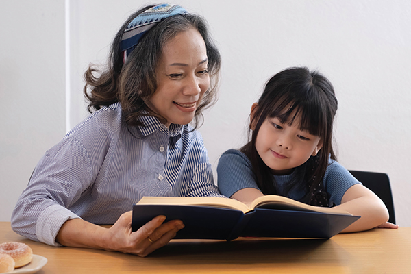 happy asian family grandmother reading to granddaughter