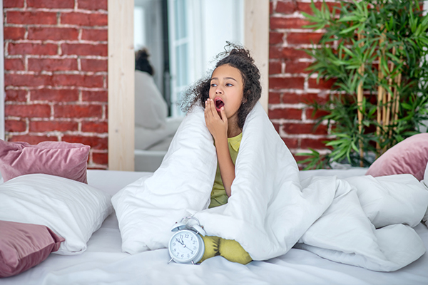 teen girl sitting under the covers on the bed