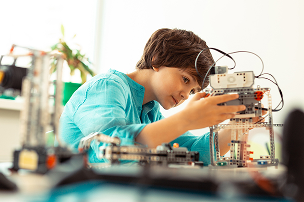 Enthusiastic elementary school pupil fixing the robot made of cconstruction set at science lesson