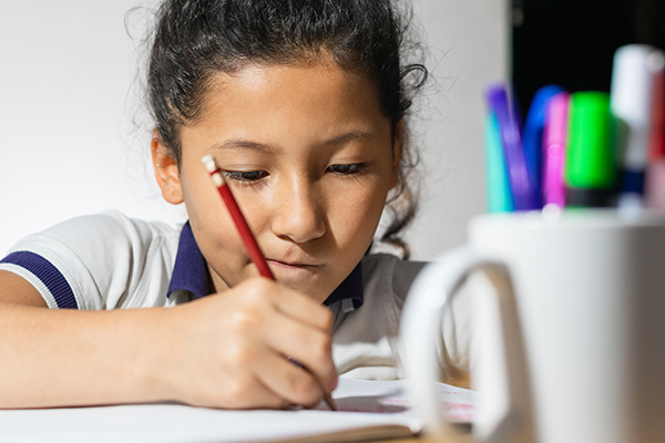 close-up of the face of a little brunette girl, very concentrated doing her homework. girl attending class.