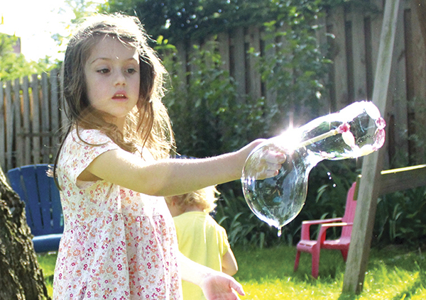 Girl is blowing bubbles with a beaded bubble wand, you make yourself.