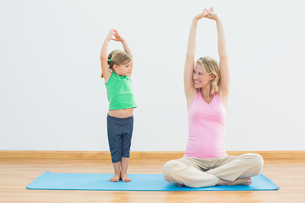 Mom and daughter are stretching together.