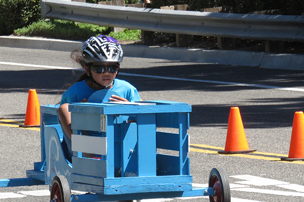 Orange crate racer careens down hill.